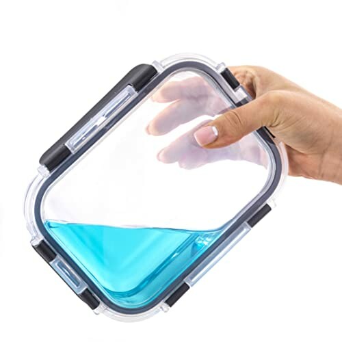 Hand holding a transparent airtight container with blue liquid.