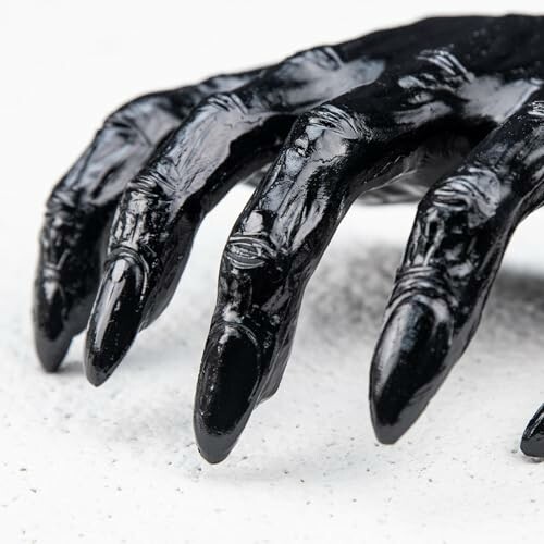 Glossy black hand sculpture with sharp nails on a white background