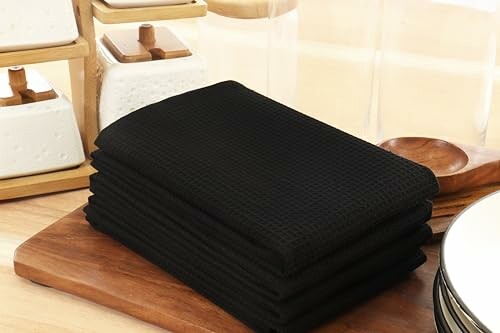 Stack of black kitchen towels on a wooden surface