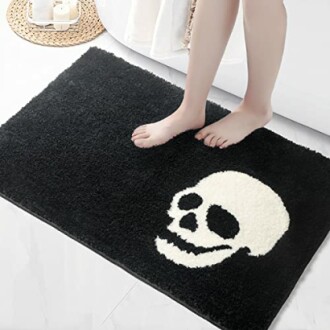 Person standing on black bath mat with white skull design.