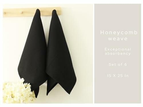 Two black towels hanging on a wooden rack with text about their features.