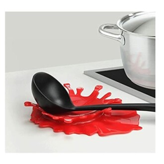 Red splash-shaped spoon rest with a black ladle beside a pot