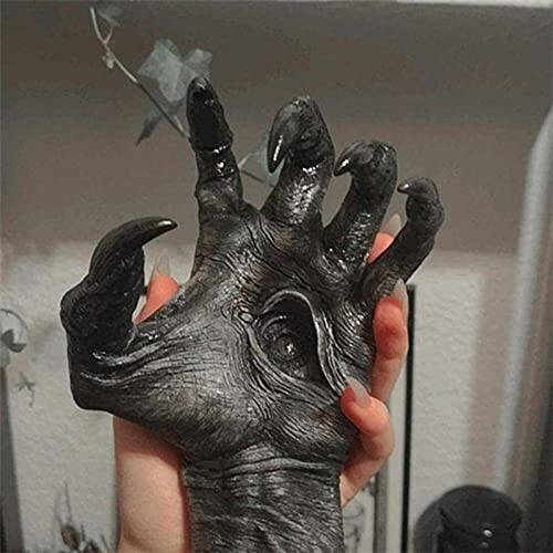 A person holding a realistic monster hand prop with dark claws.