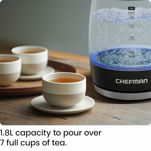 Electric kettle with tea cups on a wooden table.