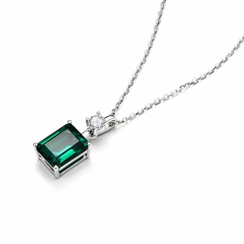 Silver chain necklace with emerald-cut green gemstone and small round diamond.