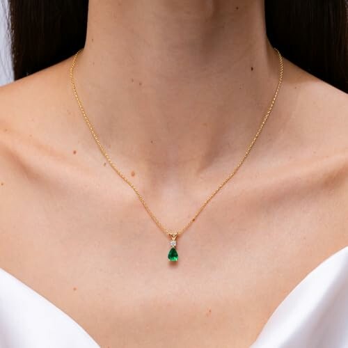 Woman wearing a gold necklace with an emerald pendant