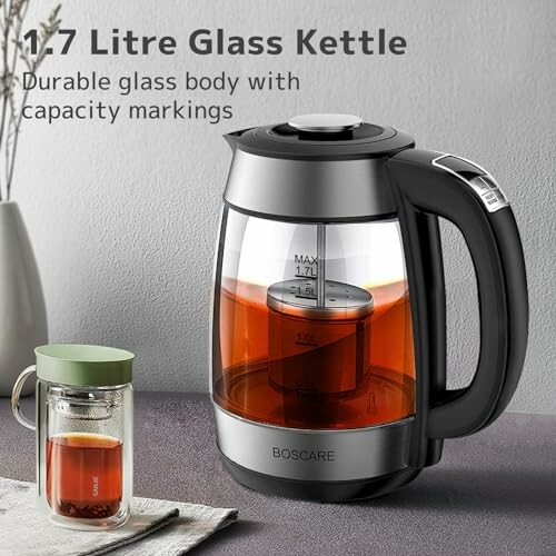 1.7 litre glass kettle with tea inside next to a glass cup.