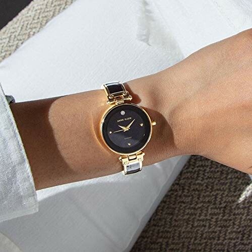 Gold wristwatch with black face on person's wrist