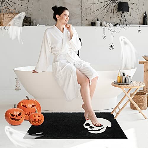 Woman in bathrobe with Halloween decor, including jack-o'-lanterns and ghost decorations.
