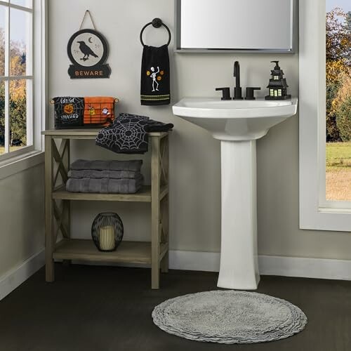 Bathroom with Halloween decorations including crow sign, themed towels, and small decor items.