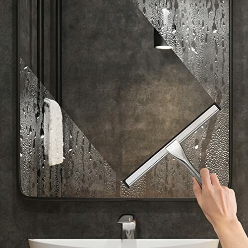 Hand using squeegee to clean foggy mirror