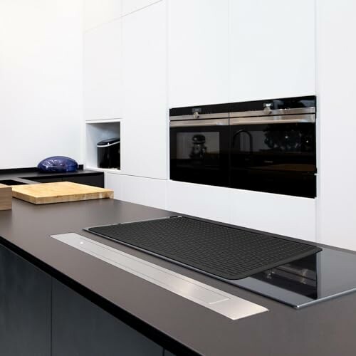 Modern kitchen with black countertop and built-in appliances.
