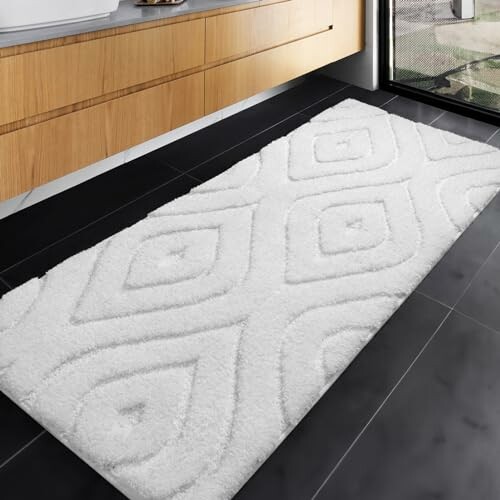 Modern kitchen with a white geometric rug on black tiled floor.
