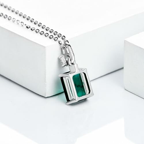 Silver necklace with emerald pendant on white background