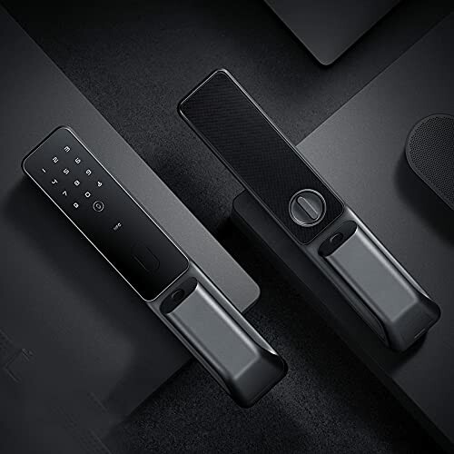 Two black smart door locks on a dark surface.
