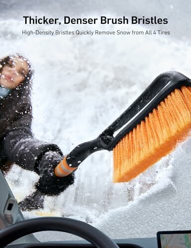 Person using a snow brush to remove snow from a car window.
