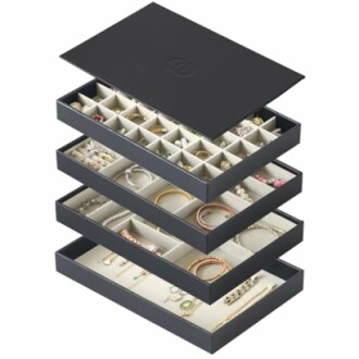 Stackable jewelry organizer with multiple compartments and assorted jewelry.