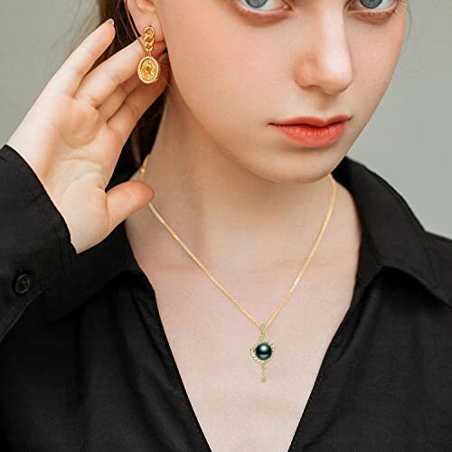 Woman wearing gold earring and necklace with black top