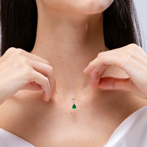 Woman wearing a gold necklace with an emerald pendant