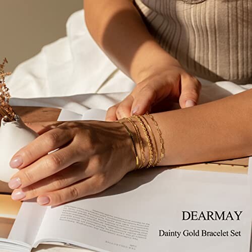 Woman wearing a dainty gold bracelet set on her wrist.