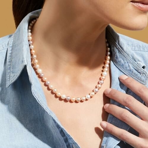 Woman wearing a pearl necklace with a denim shirt.
