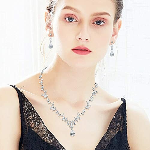 Woman wearing a silver necklace and earrings with a black lace top.